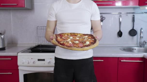 Man in white t-shirt hold and show ready pizza — Stock Video