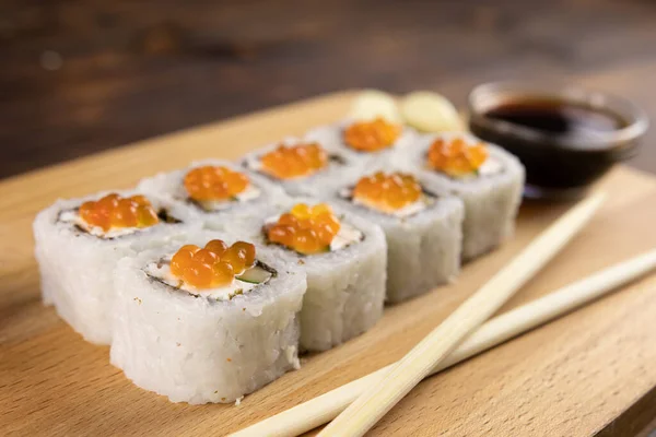 Суши с красной икрой лосося и сливочным сыром на деревянной доске — стоковое фото