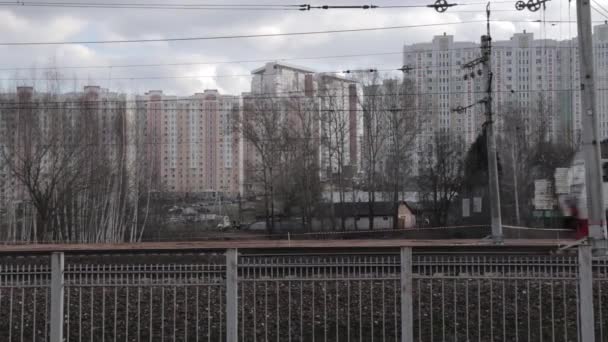 Поезд движется по городу, вид сбоку, многоэтажные жилые дома на заднем плане — стоковое видео