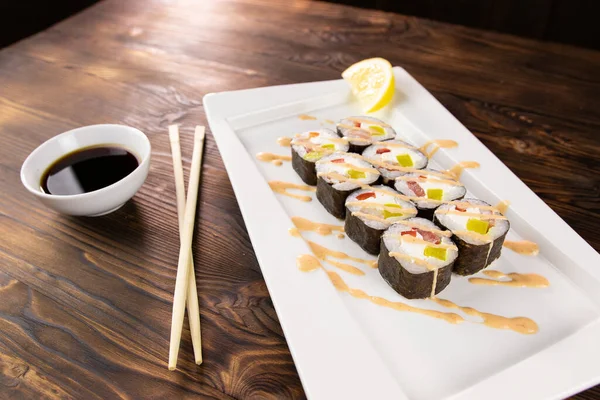 Суши-роллы с перцем и лосось с соусом на белой тарелке — стоковое фото