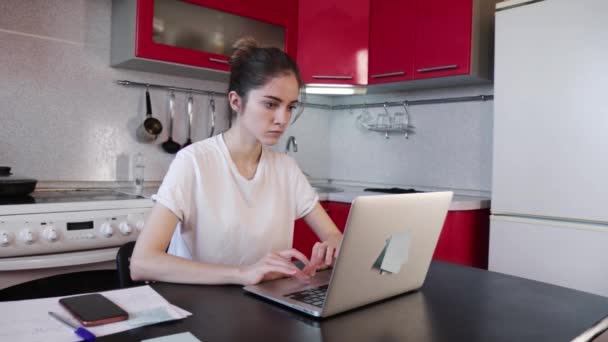 Muchacha joven que trabaja con el ordenador portátil en la cocina en casa — Vídeo de stock