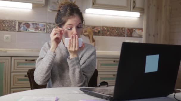 Giovane ragazza rinfresca il trucco e si prepara per la comunicazione web in cucina a casa — Video Stock