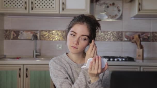 Joven niña cepillos cejas mirando en un espejo de bolsillo en casa cocina — Vídeos de Stock