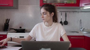 Kız evde dizüstü bilgisayarla çalışıyor, bir telefon duyuyor ve cevap veriyor.