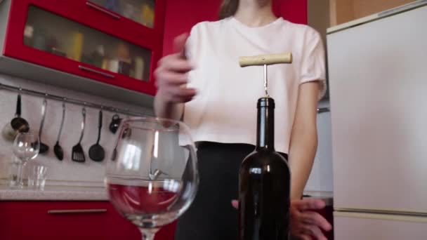 Chica en una camiseta blanca está tratando de abrir una botella de vino — Vídeos de Stock