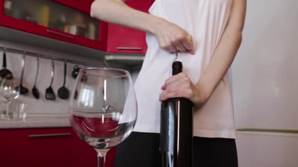 Девушка в белой рубашке пытается открыть бутылку вина — стоковое видео