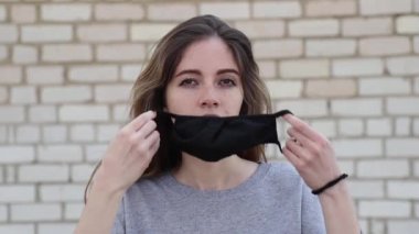 Genç kız kameraya bakıyor ve siyah bir maske takıyor.