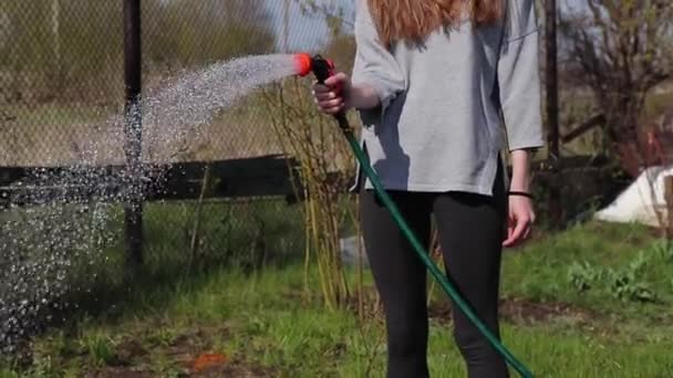 Farmer lány öntözés kerti ágy kerti permetező — Stock videók