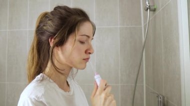 Genç kız dişlerini banyo manzarasında bir sulayıcıyla fırçalıyor.