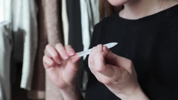 Frau schneidet Nägel mit Nagelfeile zu Hause mit Kleidung im Hintergrund Nahaufnahme DIY — Stockvideo