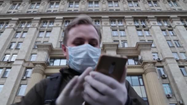 Людина в медичній масці залишає будівлю в паніці, розмовляє по телефону і тікає — стокове відео