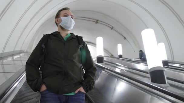 Muž v lékařské masce vstoupit do metra a jít dolů na eskalátoru — Stock video