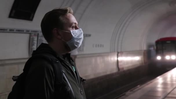 Man met medisch masker wachtend op een trein die aankomt op het metrostation — Stockvideo