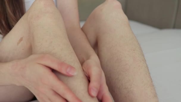 Women sitting on the couch, looking and stroking hairy legs before depilation, close up, camera moving — Stock Video