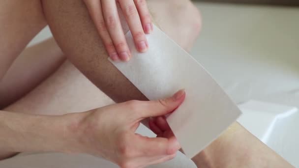 Las manos de la mujer pegan una tira de depilación en la pierna peluda y lo quitan de la piel de cerca — Vídeos de Stock