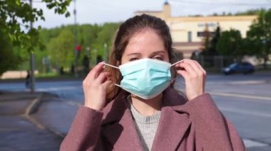  Genç bayan kameraya bakarak tıbbi bir maske takıyor.