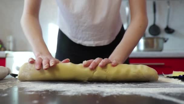 Γυναίκα κυλά μια ζύμη σε σχήμα λουκάνικου με δύο χέρια σε μια ηλιόλουστη κουζίνα, μαγειρέψτε κέικ — Αρχείο Βίντεο