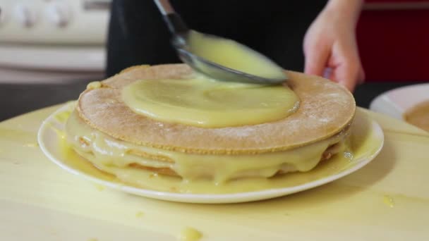 Mulher esfrega a nata em cima de um bolo que está em uma bandeja de fiação de madeira redonda de perto — Vídeo de Stock