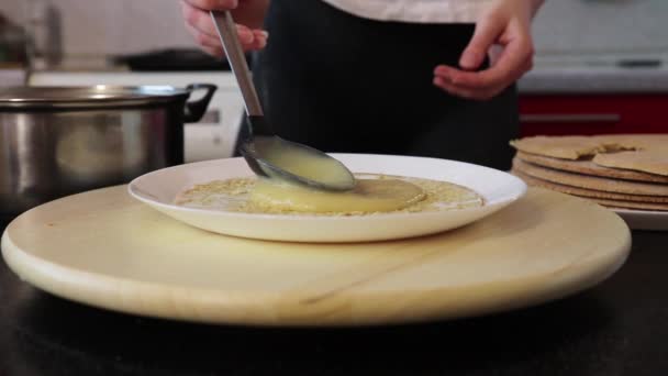 Vrouw smeert crème op een ronde taart — Stockvideo