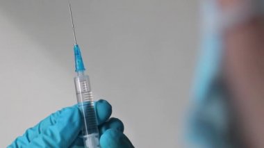 Doktor elleri şırıngayı tutuyor ve iğne yapmaya hazırlanıyor.
