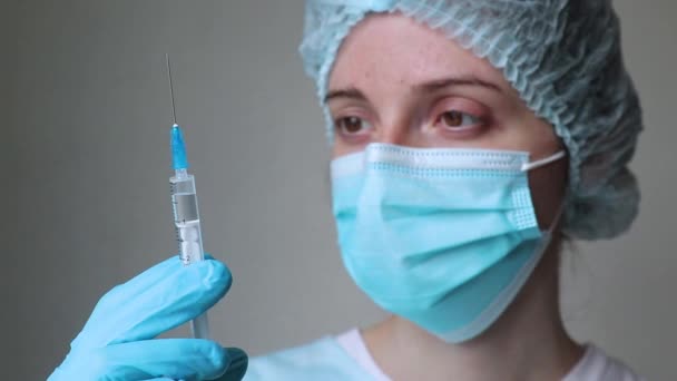 Médecin dans le masque médical regarde la seringue et se prépare à donner une injection — Video