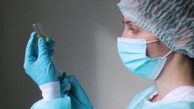 Doktor elinde bir şırınga tutuyor ve yüzüne bakıyor. 