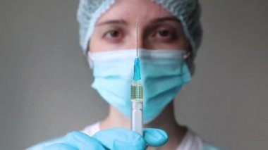 Doktor yüzünün arka planında bir şırınga tutuyor. Yakın plan.