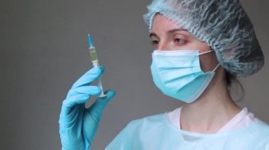 Doktor elinde bir şırınga tutuyor ve yüzüne bakıyor. 