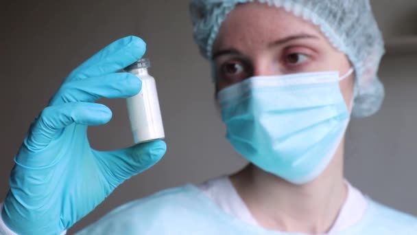 Médecin tient une ampoule avec un médicament dans les mains et le regarde — Video