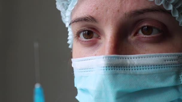 Médecin tient une seringue et regarde l'aiguille dans le fond de son visage fermer — Video