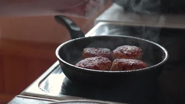 Рука піднімає кришку сковороди перевіряє готовність м'ясних кульок зубочисткою і кладе їх на тарілку — стокове відео
