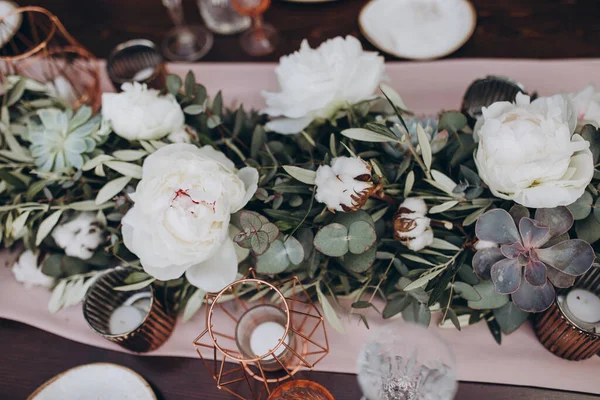 結婚式の装飾 木製のバンケットテーブルには ガラス プレート キャンドル テーブルは綿とユーカリの枝の組成物で飾られており プレートはナプキンやイタリアの緑の小枝で飾られています — ストック写真