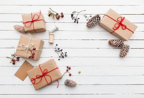 Homemade wrapped rustic brown paper packages with various natural things on white wooden surface