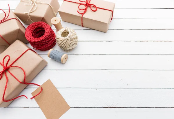 Homemade wrapped rustic brown paper packages on white wooden surface