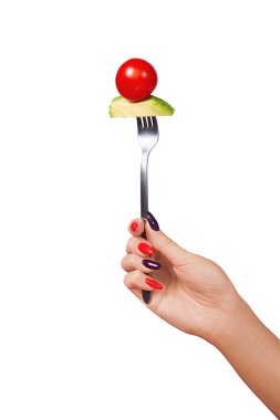 Gümüş çatallı bir domates ve avokado seti tutan güzel bir kadın eli..