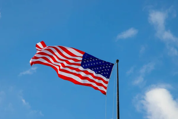 Flag af USA isoleret på den blå himmel med de hvide skyer i New York, USA. 25. december 2018 - Stock-foto