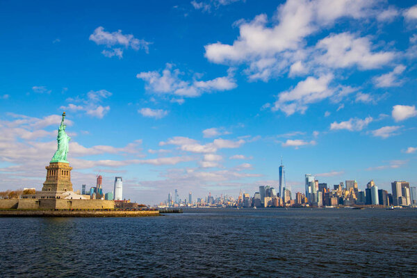 Statue of Liberty and New York Skyline isolated on the blue sky with white clouds