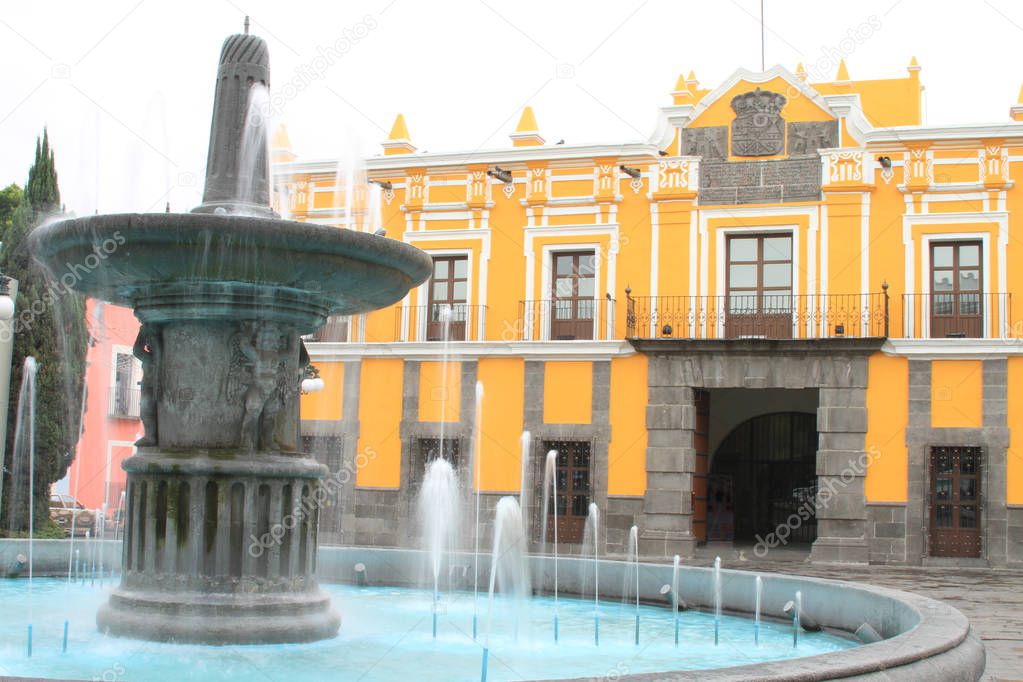 Colonial Fountain in front of yellow building