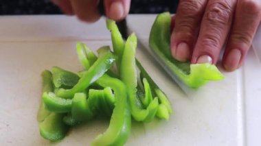 Beyaz tahta üzerinde yeşil biber kesen eski el