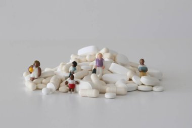 Seçici odak noktasındaki beyaz hapların arasında küçük heykelcikler