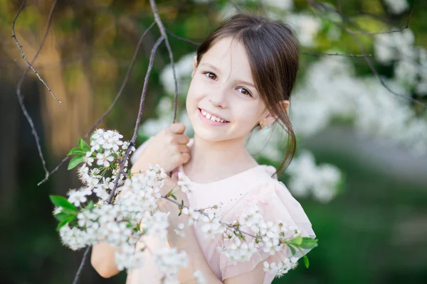 Sevimli küçük kız çiçek açan elma ağacı bahçede