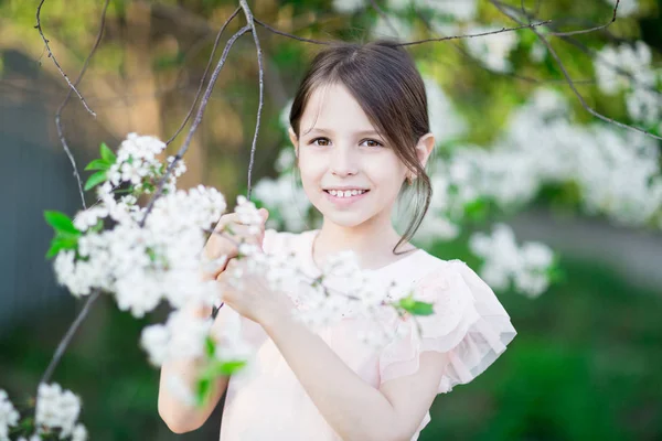 Bedårande liten flicka i blommande apple tree garden Stockbild