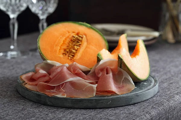 Melon and italian prosciutto on dark background — Stock Photo, Image