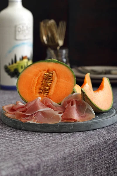 Melon and italian prosciutto on dark background — Stock Photo, Image