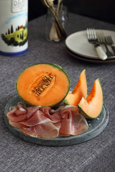 Melon and italian prosciutto on dark background — Stock Photo, Image