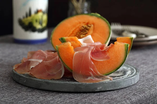 Melon and italian prosciutto on dark background — Stock Photo, Image