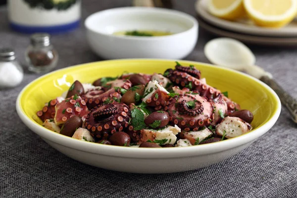 Ensalada de pulpo en plato de cerámica sobre fondo de mesa de cocina —  Fotos de Stock