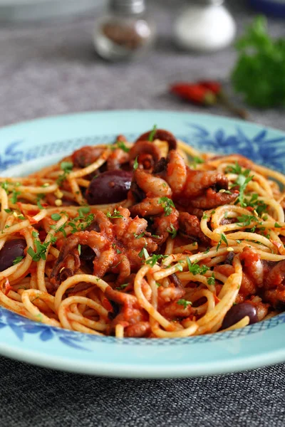 Итальянская макароны с осьминогом в томатном соусе на кухонном столе — стоковое фото