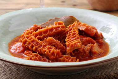 tradional tripe in tomato sauce in rustic ceramic plate on kitchen table background