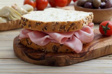  İştah açıcı sandviç jambon dilimleri Ahşap doğrama tahtası, cherry domates, zeytin ve turşu ile